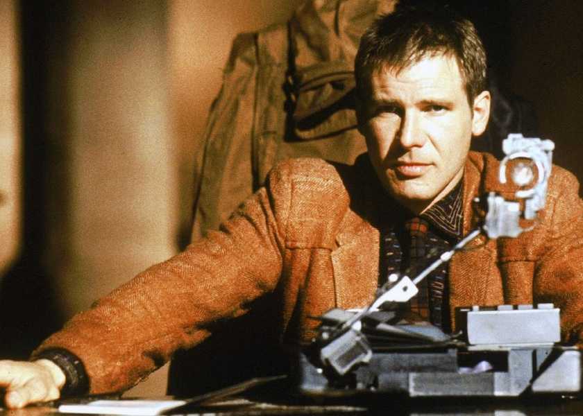 Decker sits behind a desk in Blade Runner