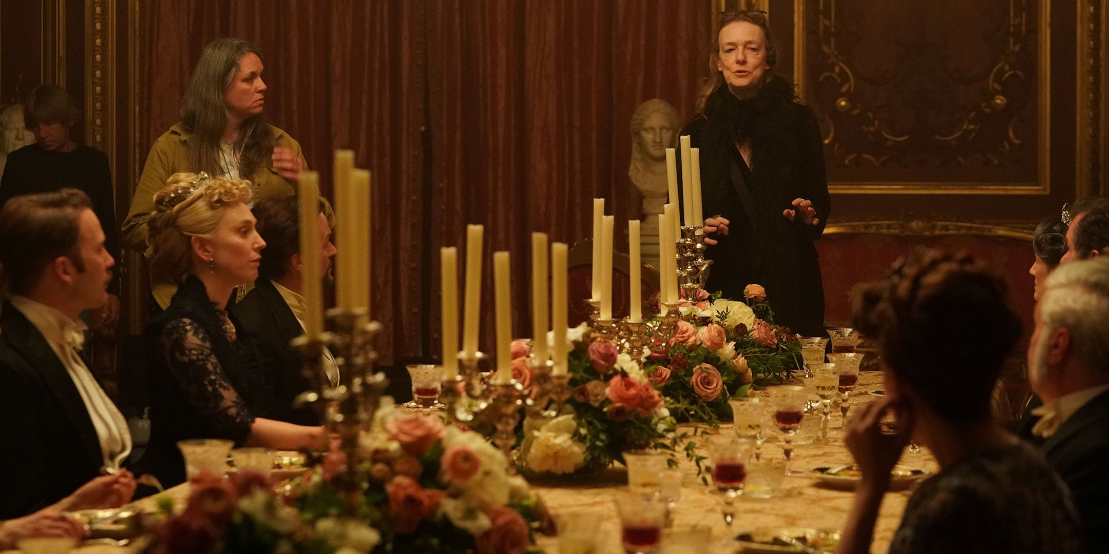 Deborah Kampmeier directing a group of people at a large dining table in The Gilded Age season 3