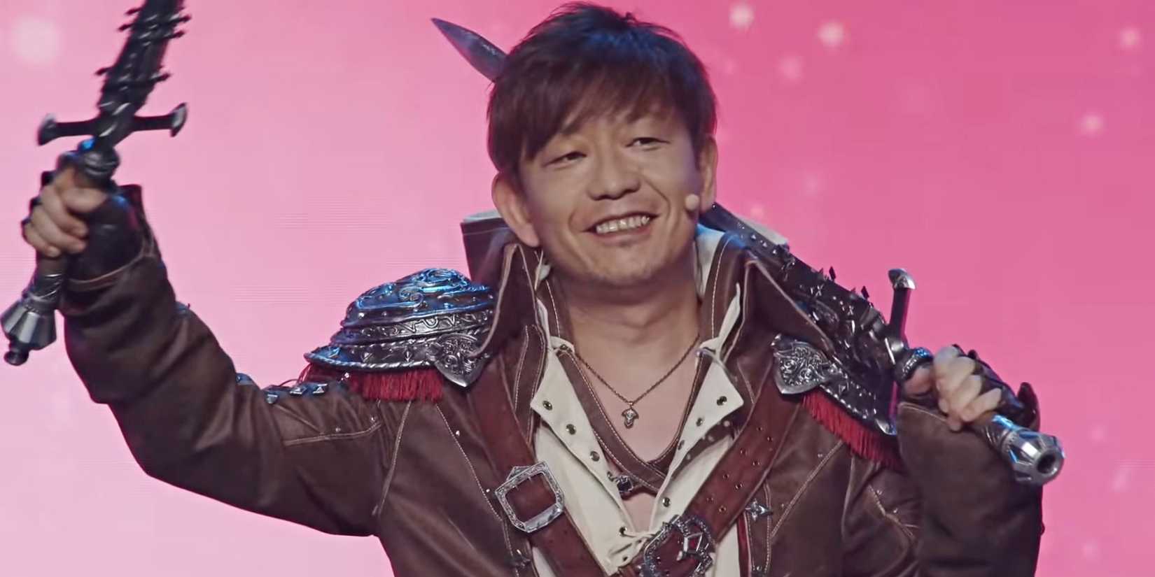 Yoshi-P sorride e saluta con una spada indossando un cosplay Viper da Final Fantasy 14.