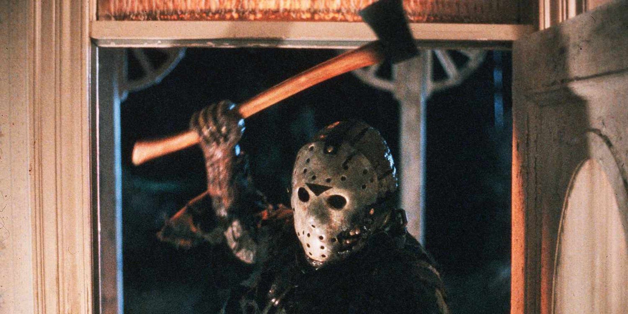 Jason holds up an axe while standing in a doorway in Friday the 13th Part VII