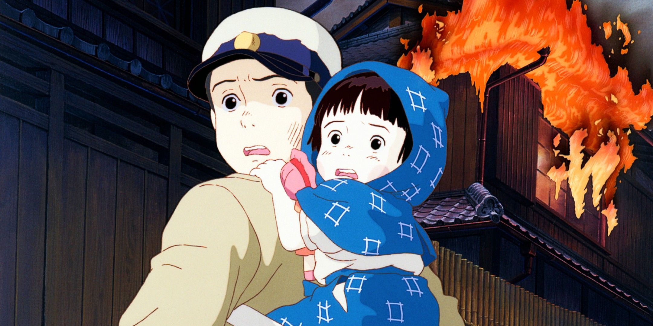 Seita holds Setsuko on his back as a building catches fire behind them in Grave of the Fireflies