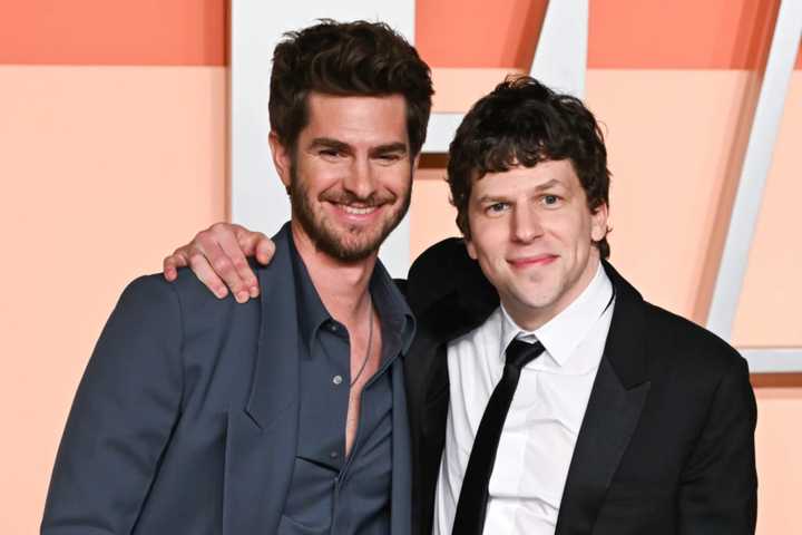 Jesse Eisenberg with his arm around Andrew Garfield's shoulder on a red carpet