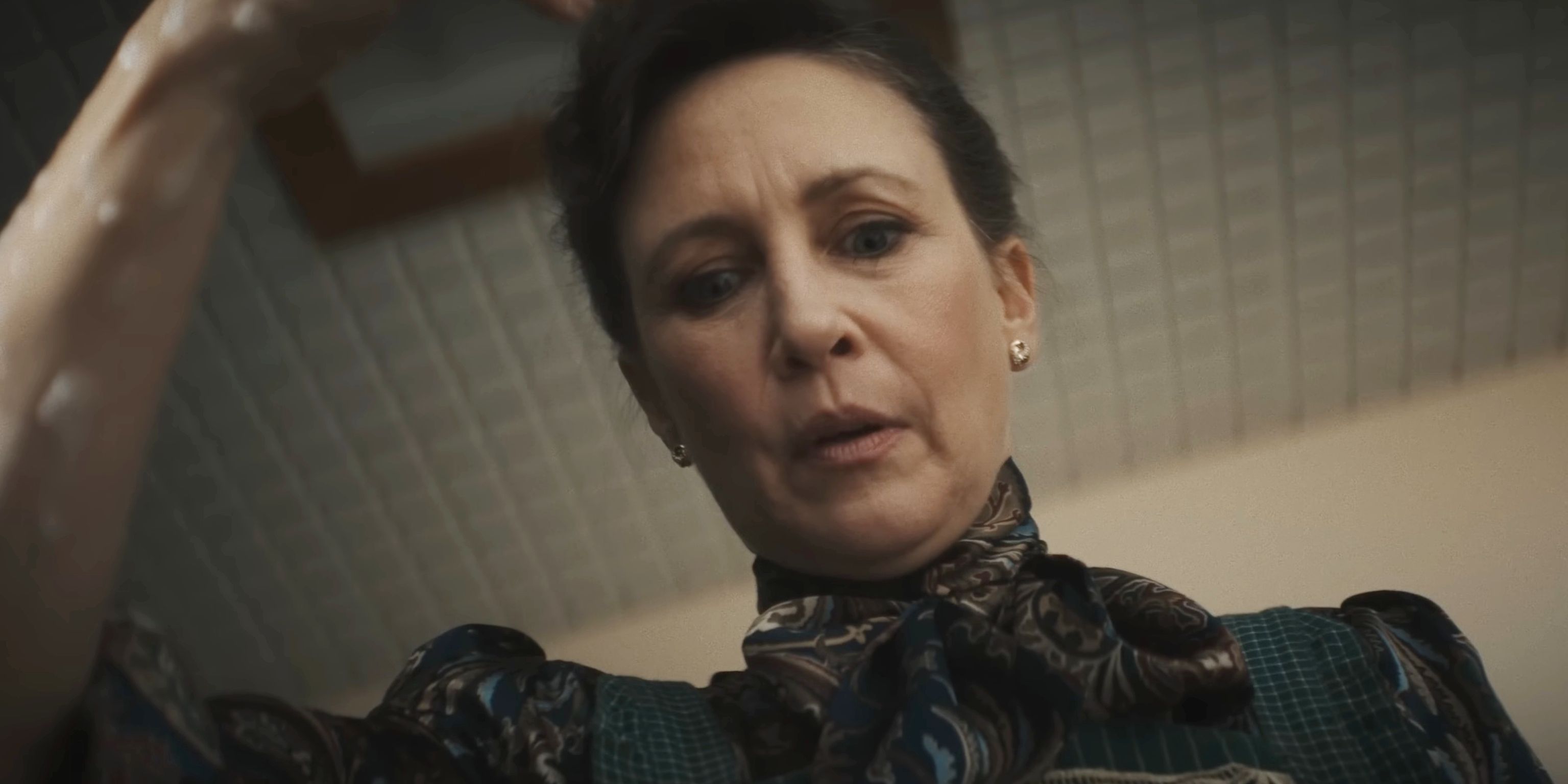 Lorraine Warren staring down at something with a concerned expression in The Conjuring Last Rites