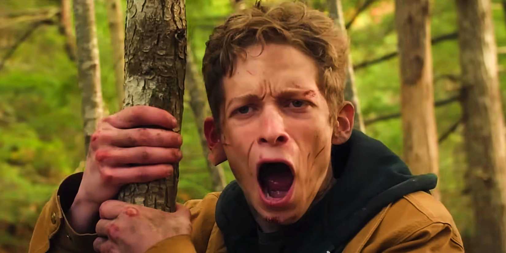 Luke screaming while holding onto a tree in The Institute