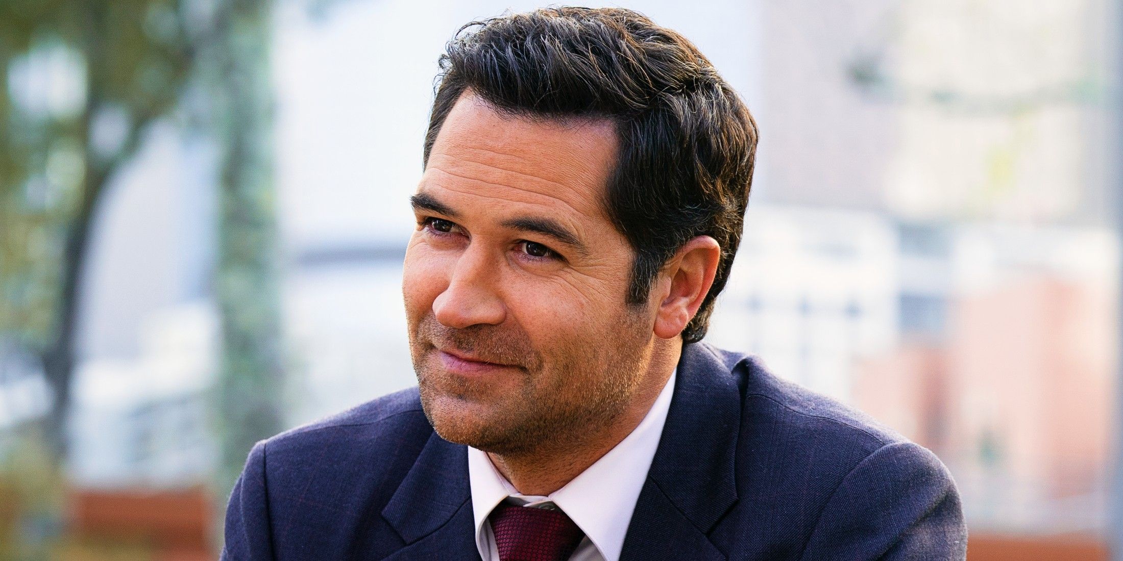 Manuel Garcia-Rulfo as Mickey Haller soft smiling at someone off-screen in The Lincoln Lawyer