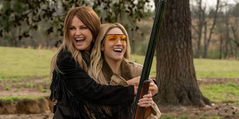 Margo hugs Sophe as she holds a gun in The Hunting Wives season 1