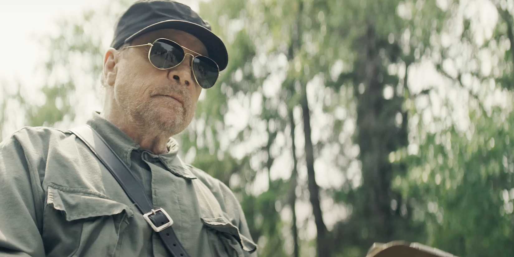 Mark Hamill wears aviator glasses and looks menacing in a scene from The Long Walk