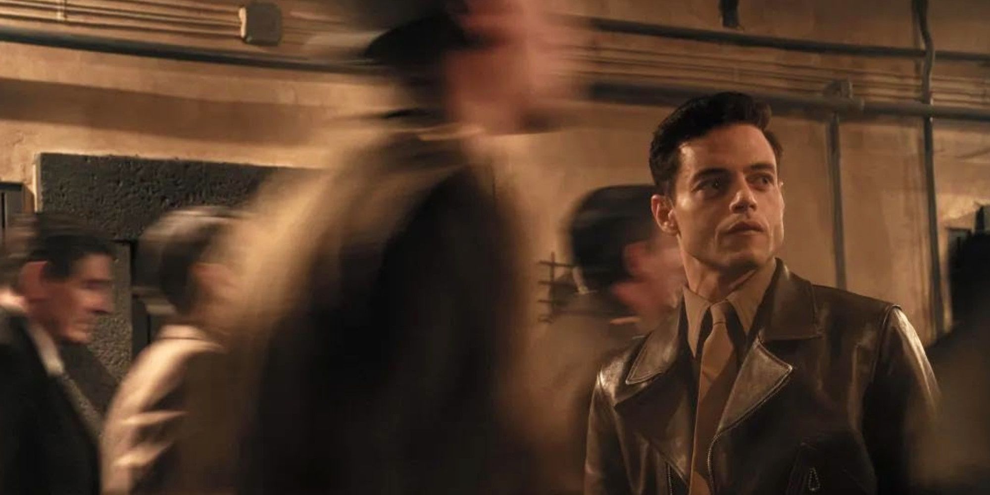 Nuremberg Rami Malek surrounded by a blur of people in motion 