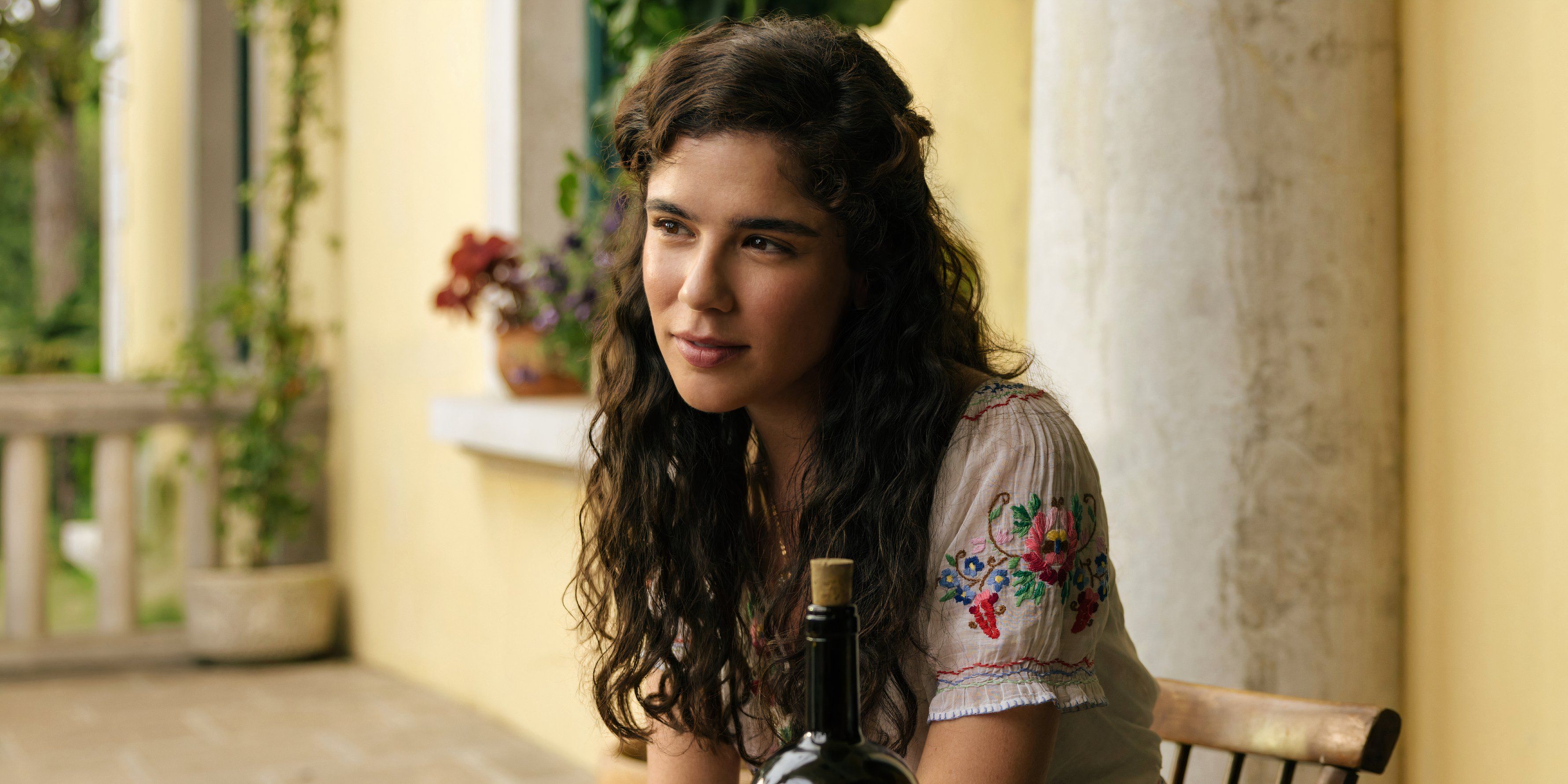 Paloma sitting at a table in The Buccaneers season 2 episode 5