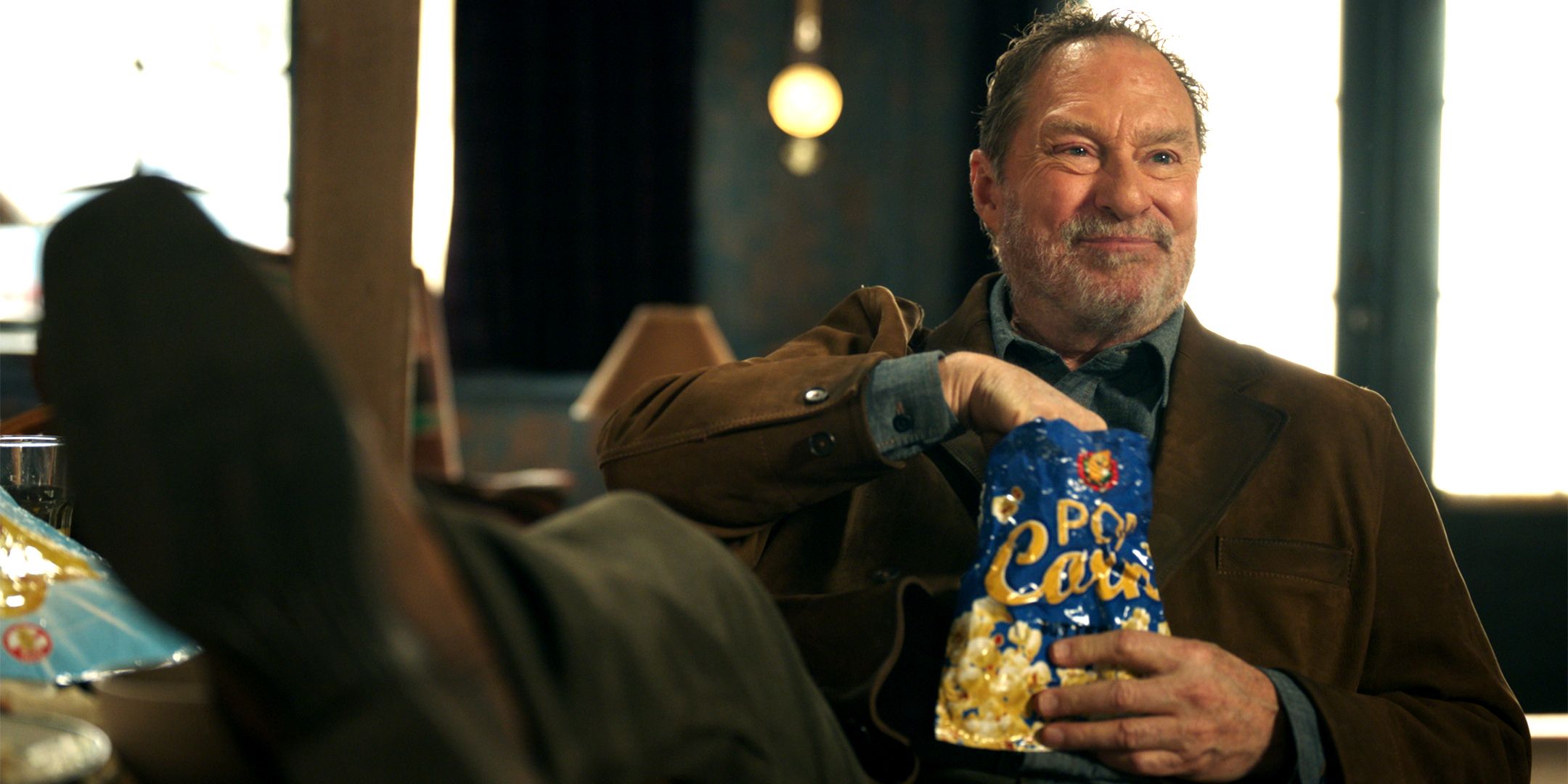 Stephen Root's Ed laying with his feet up and eating popcorn in Resident Alien season 4