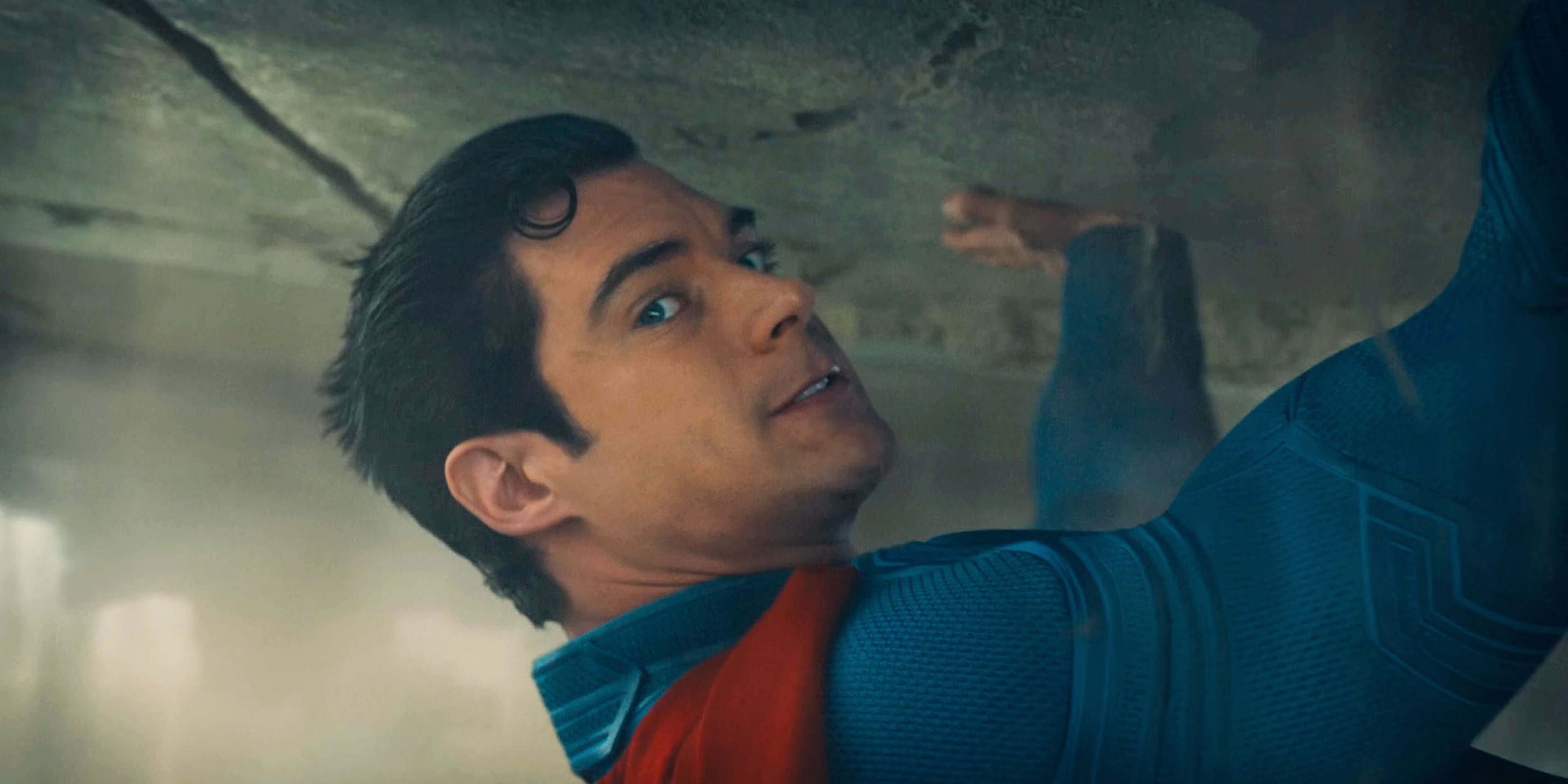 Superman straining while holding up a collapsed building in Superman 2025