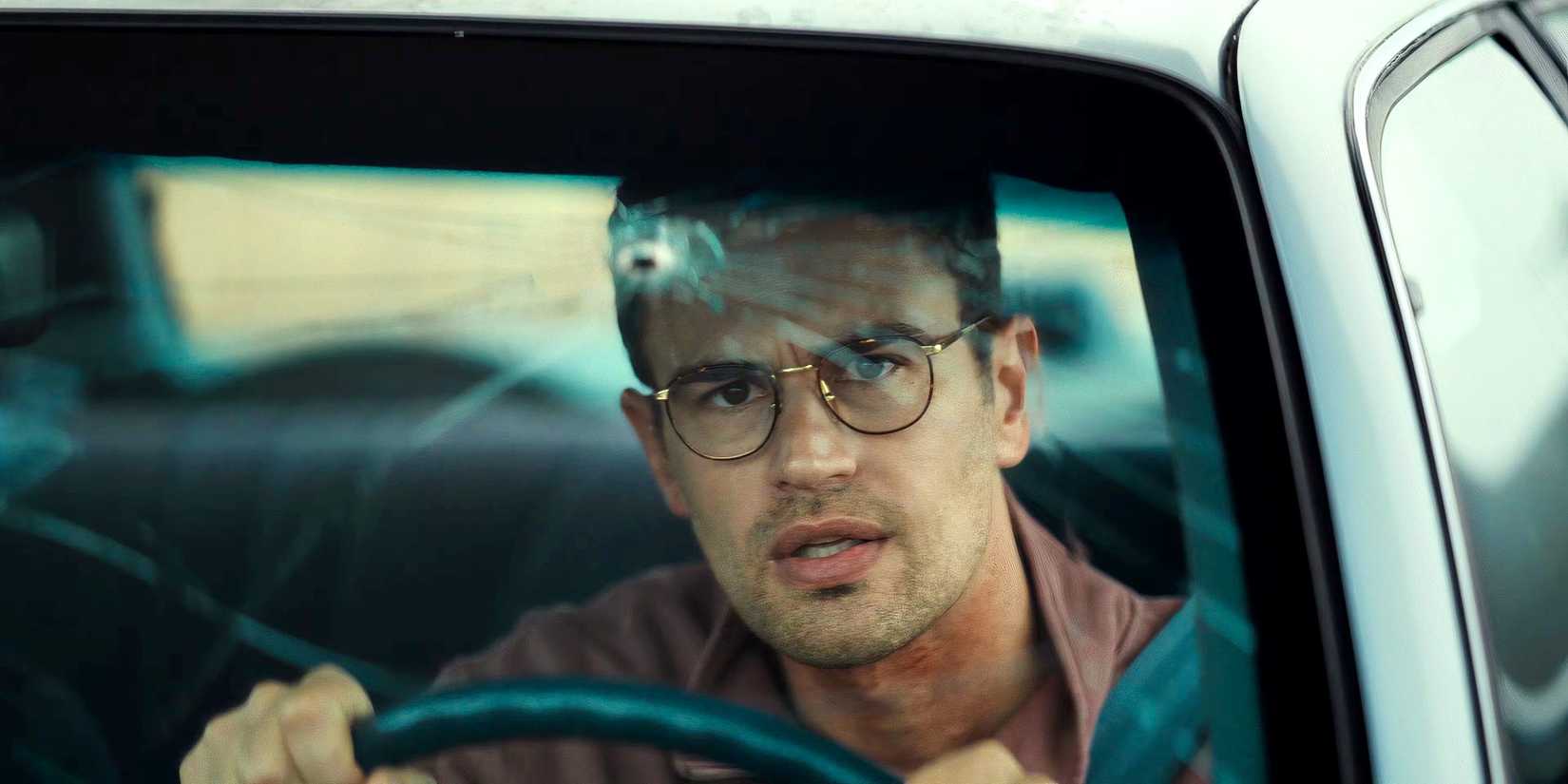 Theo James looks at a bullet hole in his car windshield in The Monkey