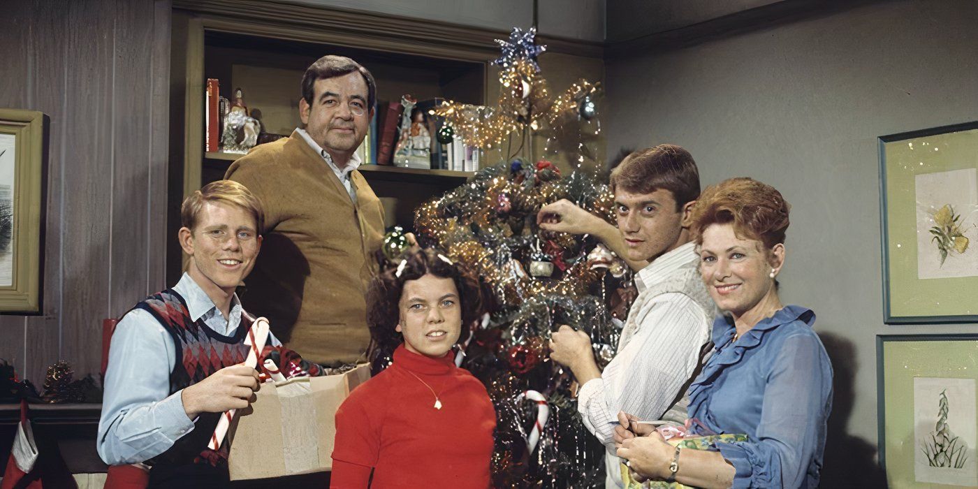 Richie, Joanie, Howard, Chuck, and Marion posing in front of a Christmas tree as they decorate it in the Happy Days season 2 epsiode “Guess Who's Coming to Christmas.” 