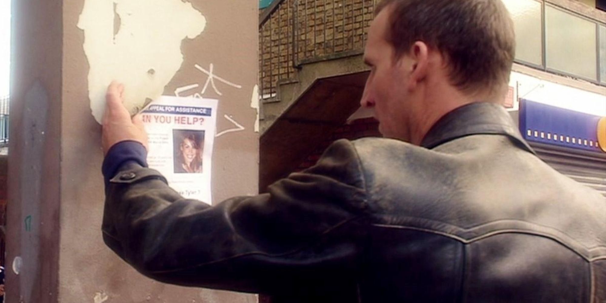 The Ninth Doctor looking at Rose's missing poster outside her home in shock in the Doctor Who season 1 episode "Aliens of London."