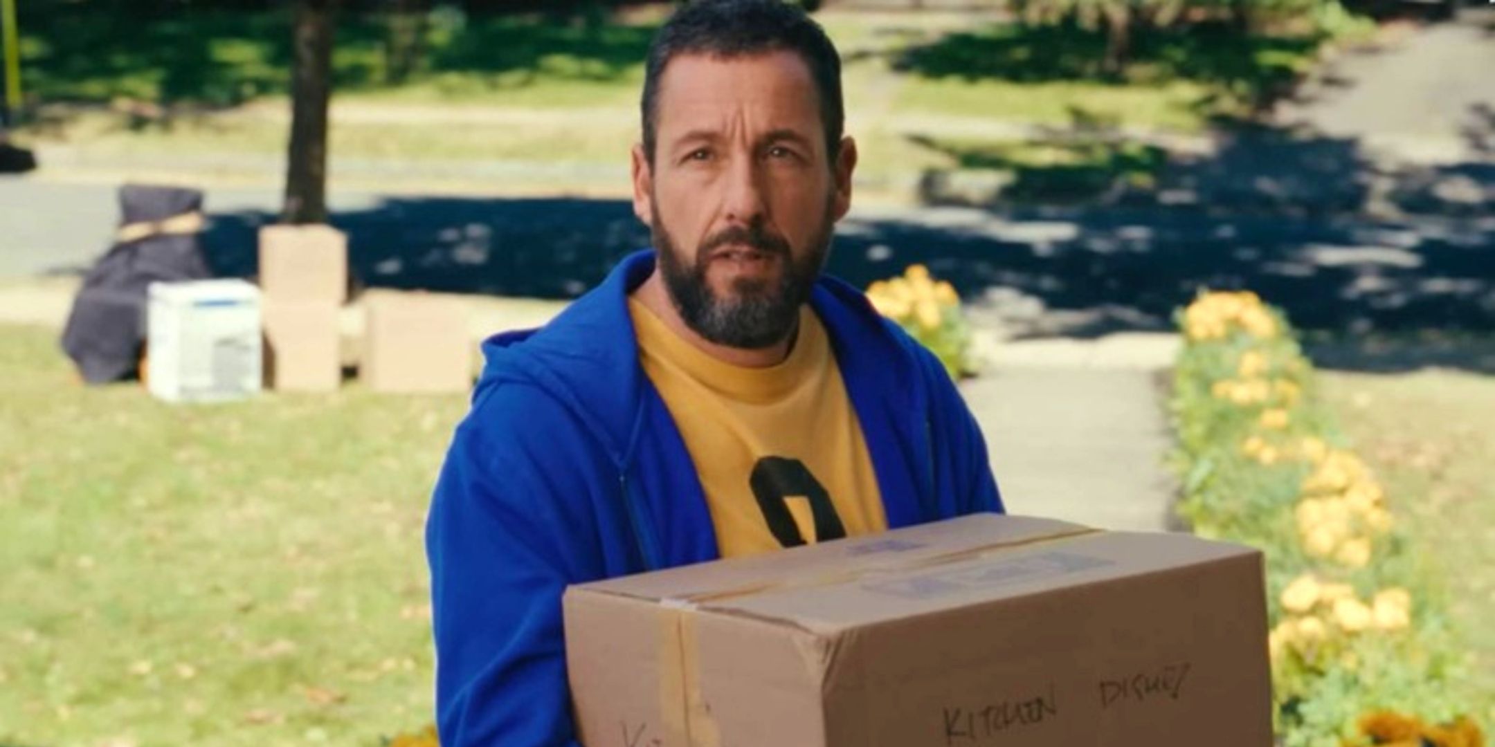 Adam Sandler holding a big box in Happy Gilmore 2