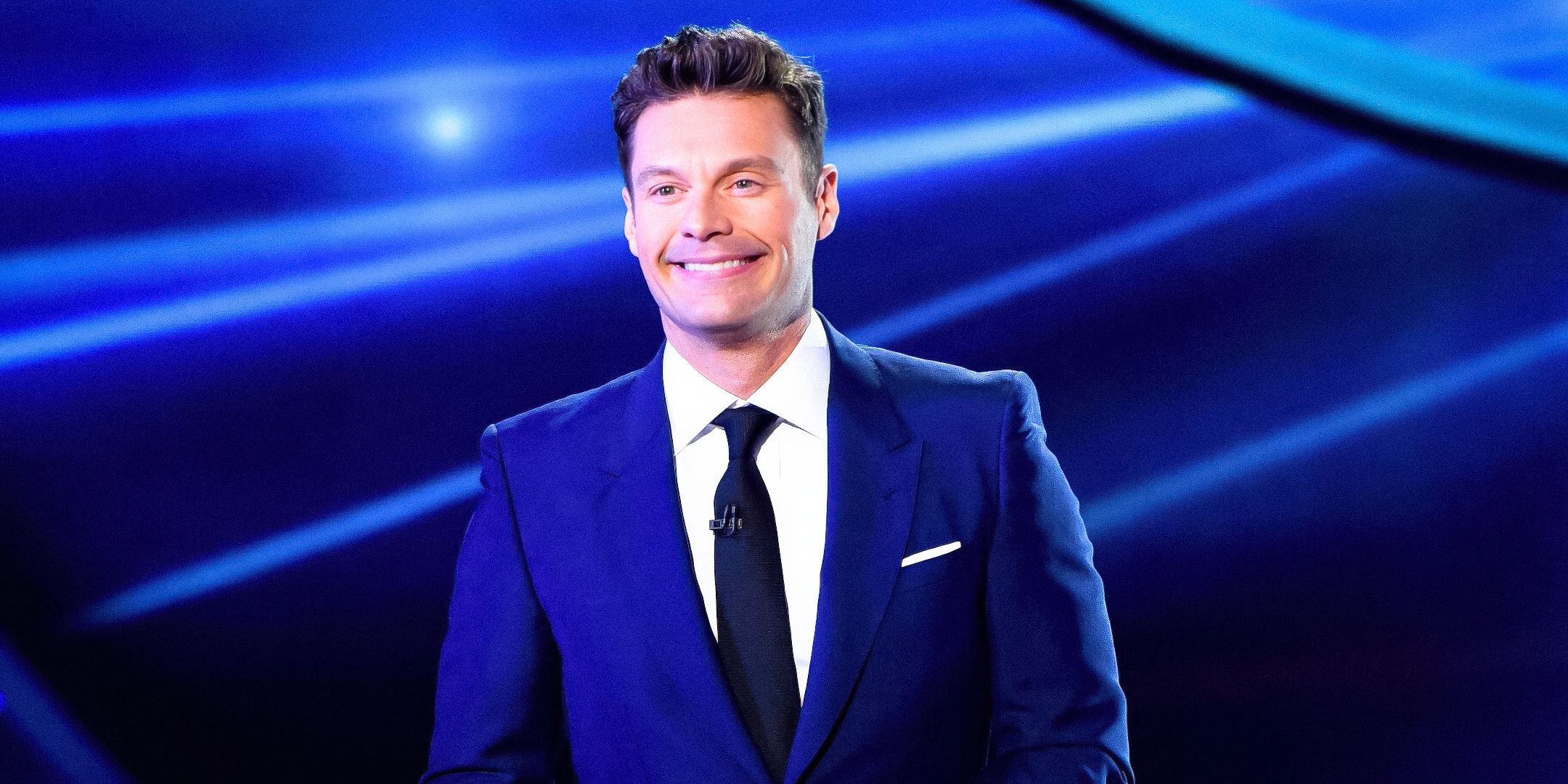 Wheel of Fortune Ryan Seacrest smiling with blue background