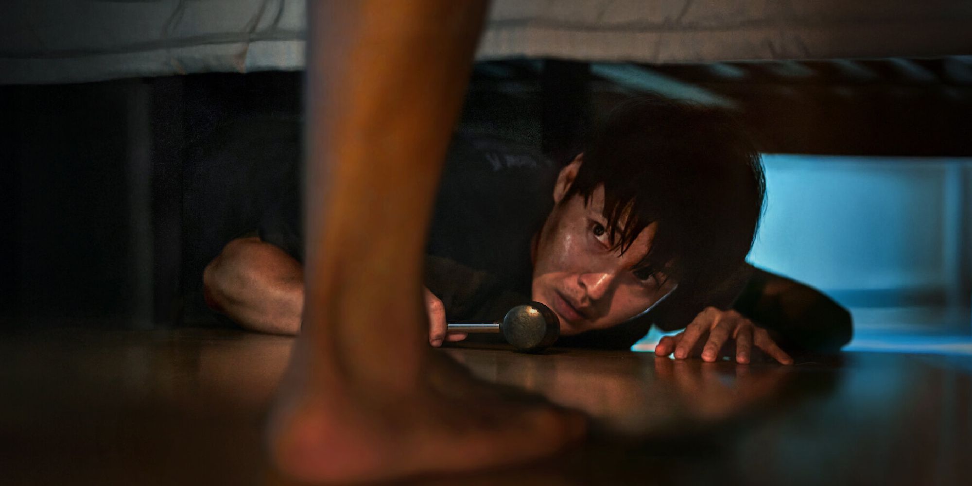 Woo-sung hides under a bed in Netflix's Wall to Wall