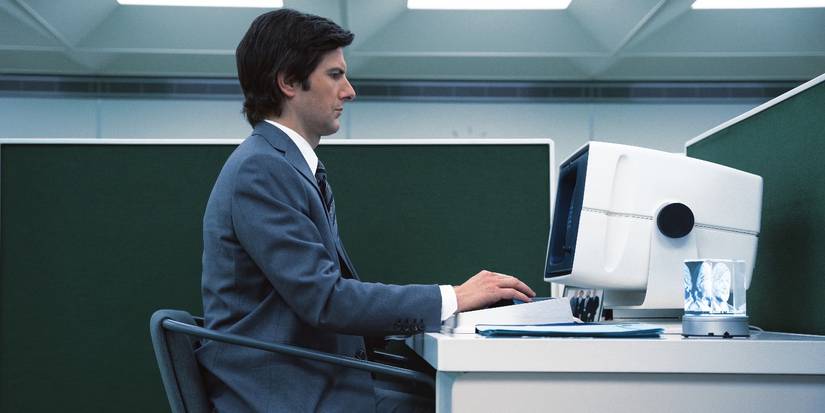 Adam Scott as Mark S sits at his desk in Severance