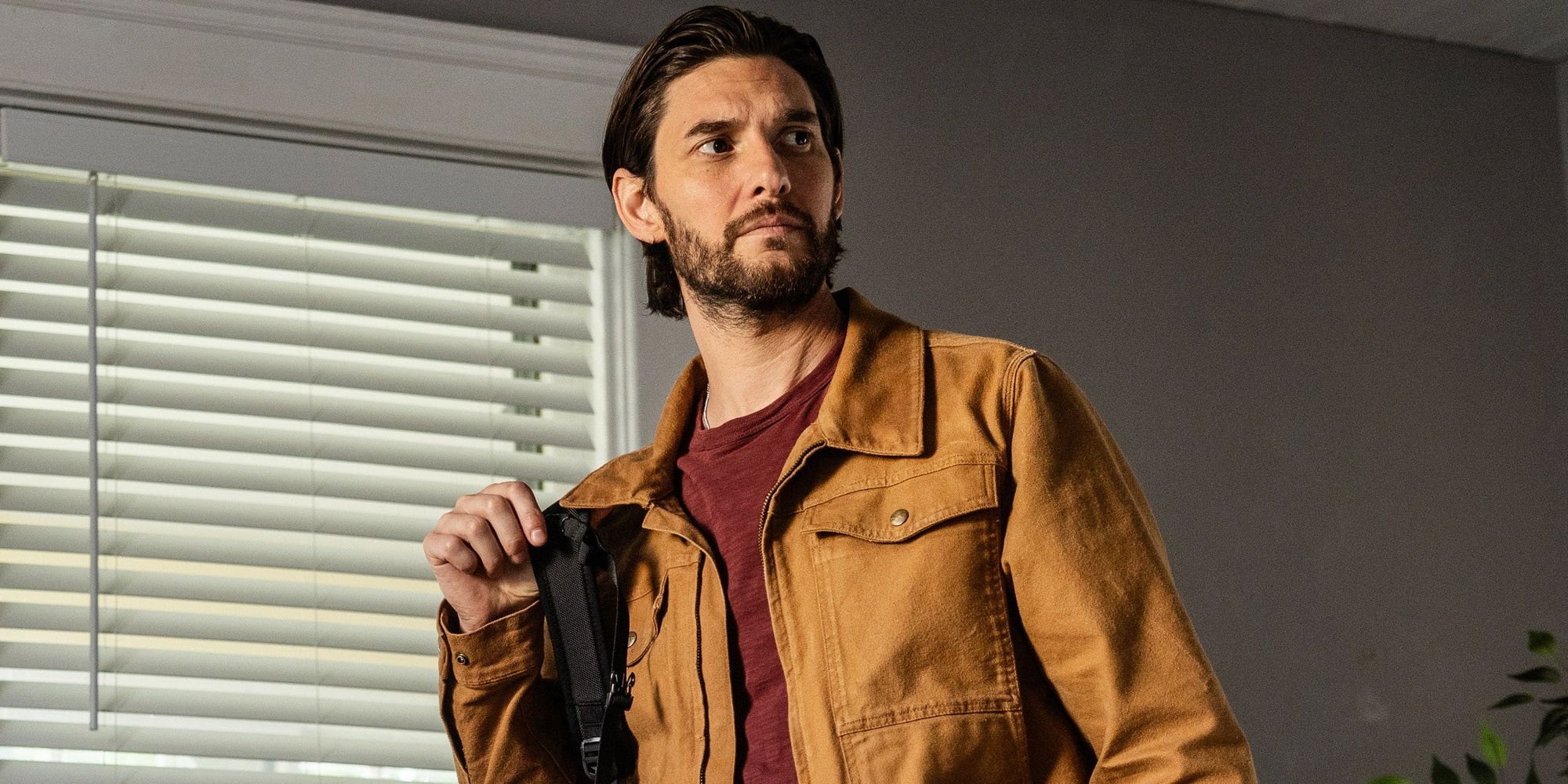 Ben Barnes holds a backpack and looks up in The Institute