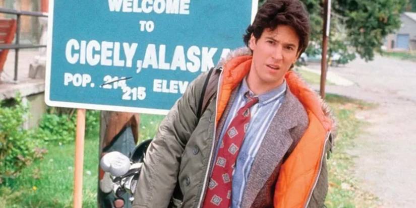 Dr. Joel Fleischman in front of the Cicely Alaska welcome sign in Northern Exposure