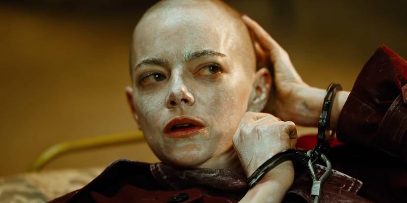 Emma Stone handcuffed and touching her bald head in Bugonia