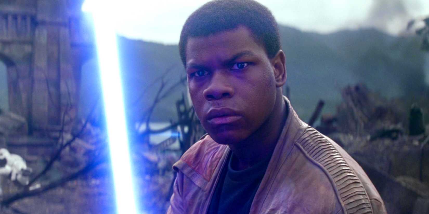 John Boyega holding a lightsaber as Finn in Star Wars The Force Awakens