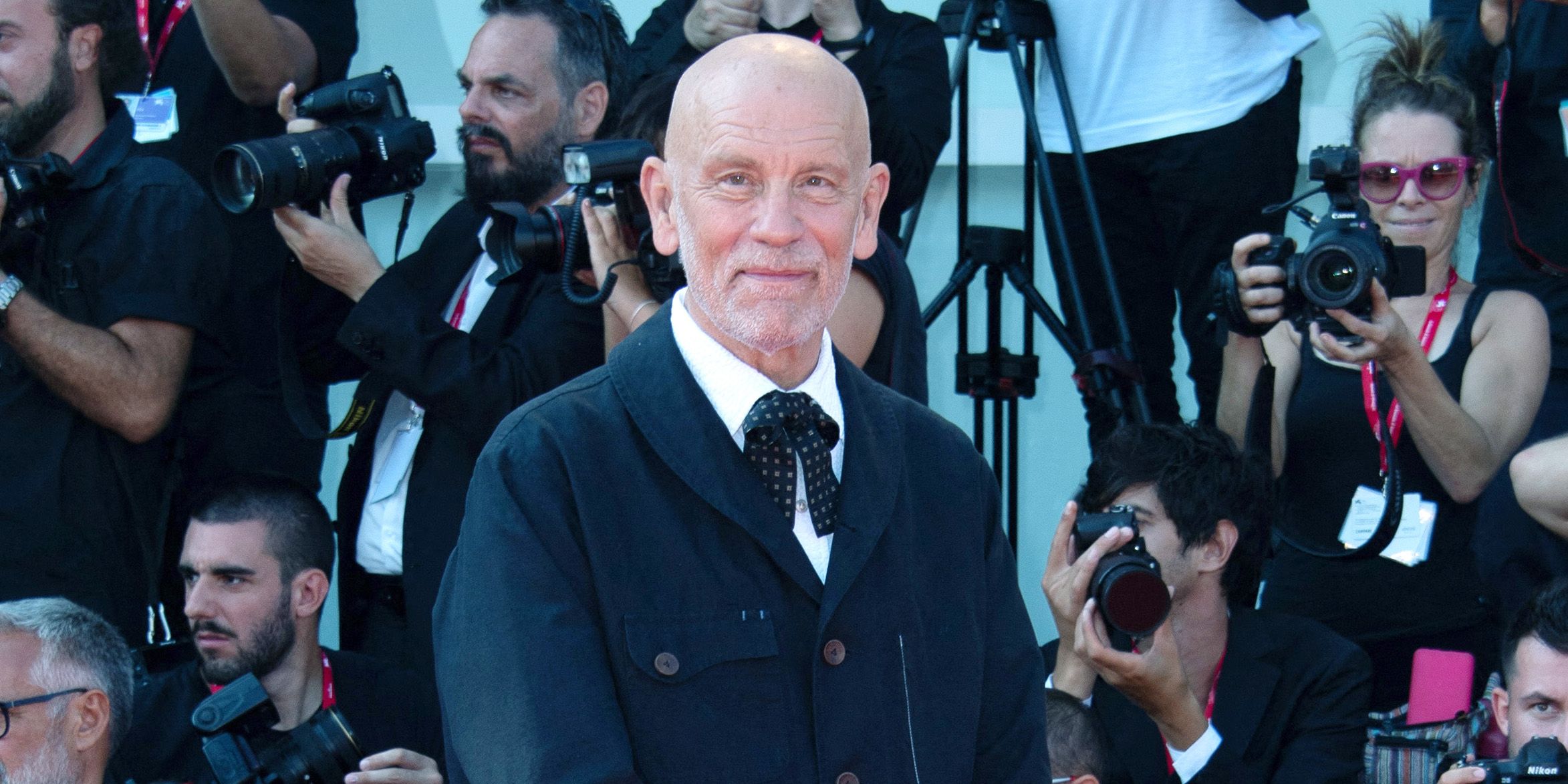 John Malkovich circondato dai fotografi sul red carpet
