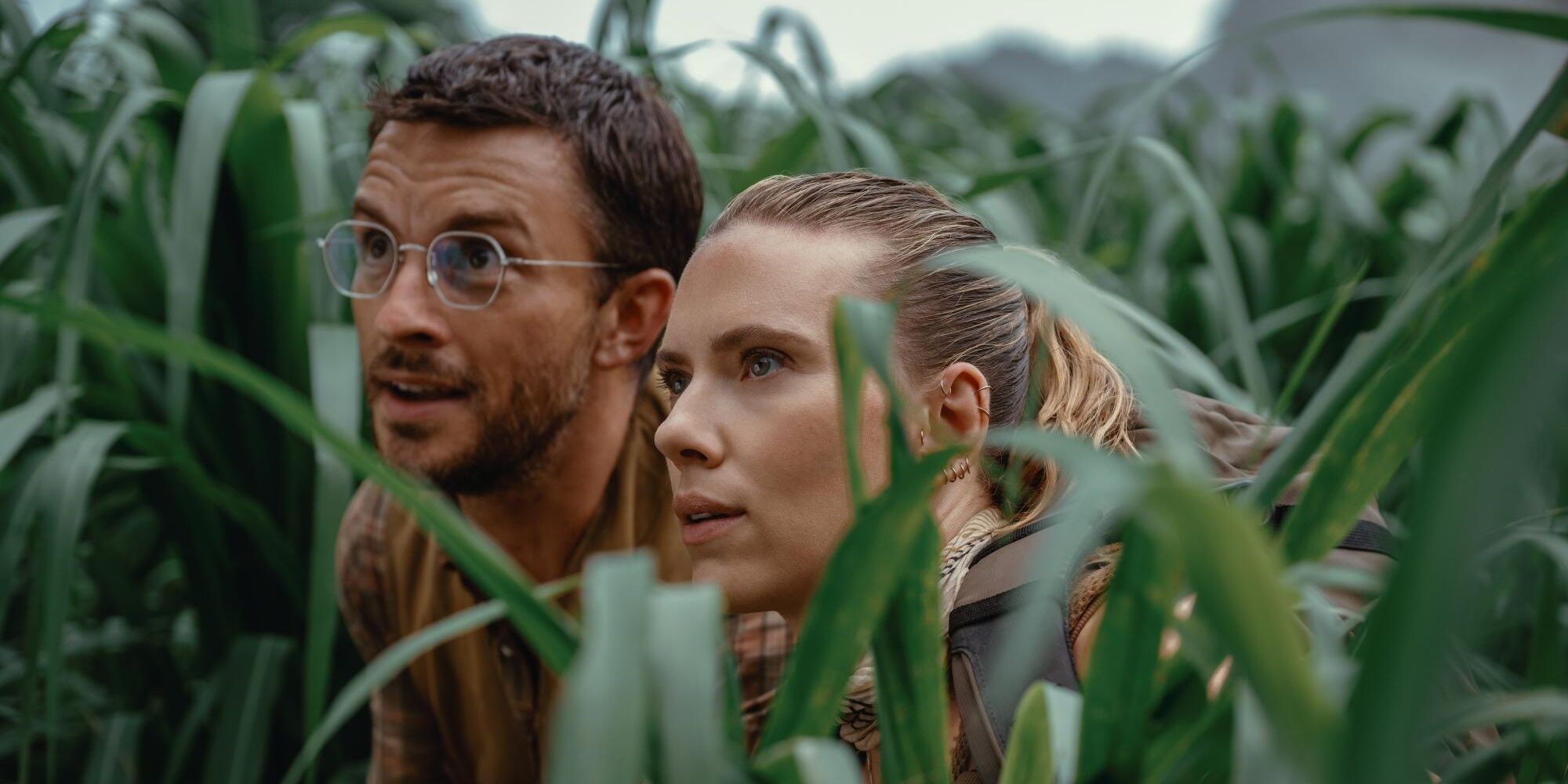 Jonathan Bailey and Scarlett Johansson staring at a dinosaur in Jurassic World Rebirth