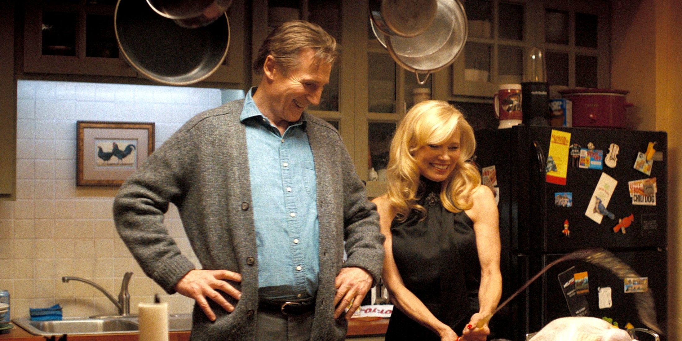 Liam Neeson and Pamela Anderson smiling while in the kitchen in The Naked Gun