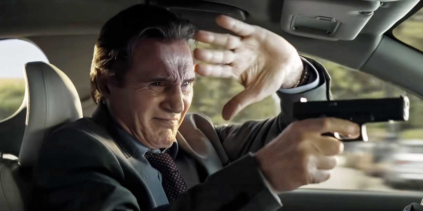 Liam Neeson holding a hand up and shooting at his windshield in The Naked Gun