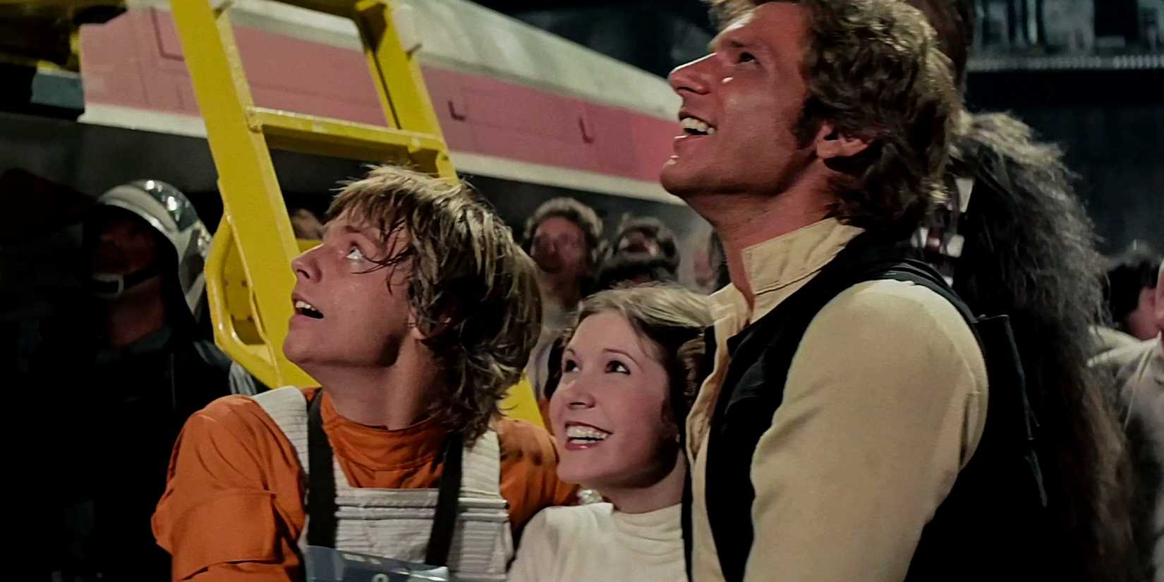 Luke Leia and Han Solo arm in arm and smiling at the end of Star Wars A New Hope