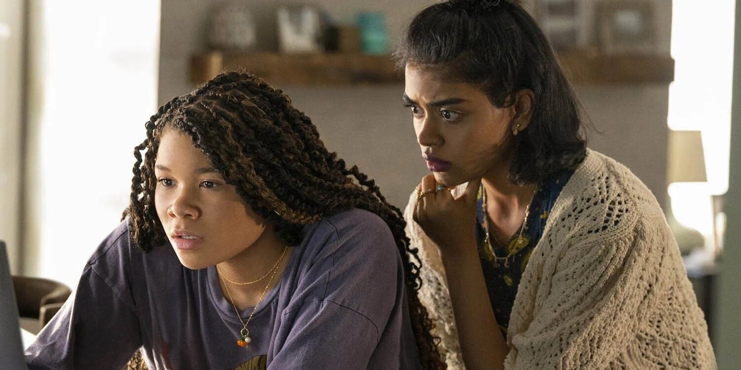 Storm Reid and Megan Suri huddled together looking at a computer in Missing