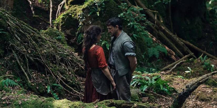Paul Mescal & Jessie Buckley standing close in a forest in Hamnet