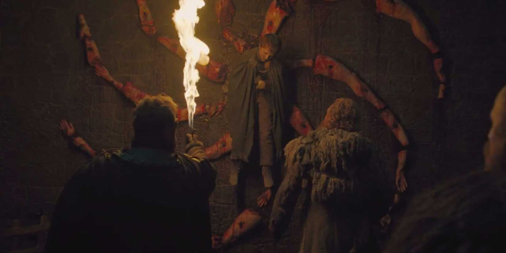 People holding a flame to a bloody spiral with a boy nailed to the center in Game of Thrones.