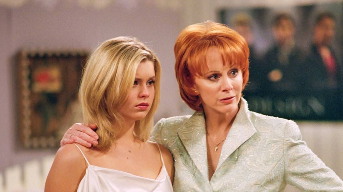 Reba puts a protective arm around a young girl in Reba