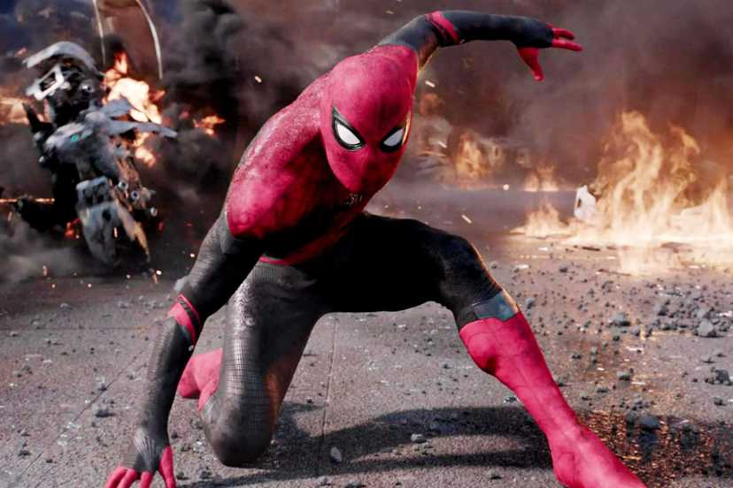 Spider-Man strikes a superhero landing pose with destruction behind him in Spider-Man Far From Home