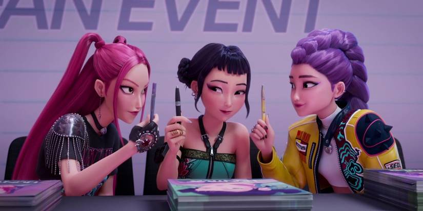 the three members HUNTR/X sitting together at the signing, holding up pens, in KPop Demon Hunters