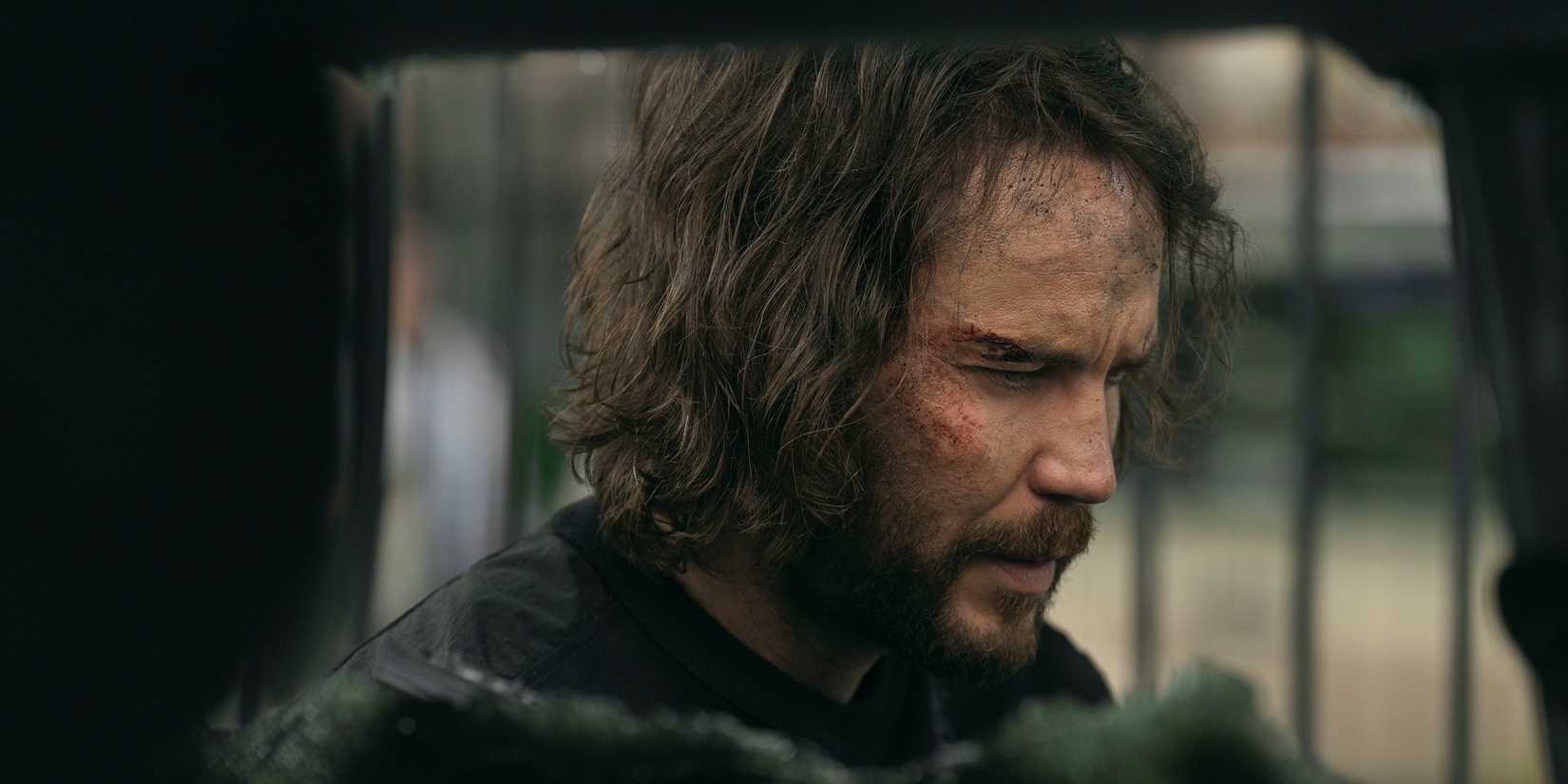 Taylor Kitsch's Ben looking beat up next to a blown-up car in The Terminal List: Dark Wolf