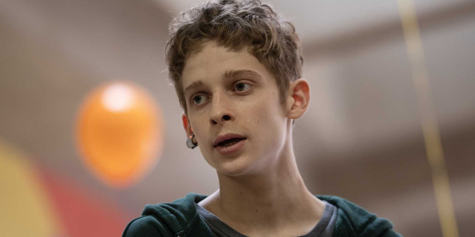 Luke Ellis (Joe Freeman) looking ahead while a balloon floats behind him in The Institute