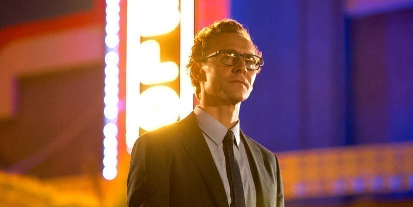 Tom Hiddleston standing in front of a movie theater in The Life of Chuck.