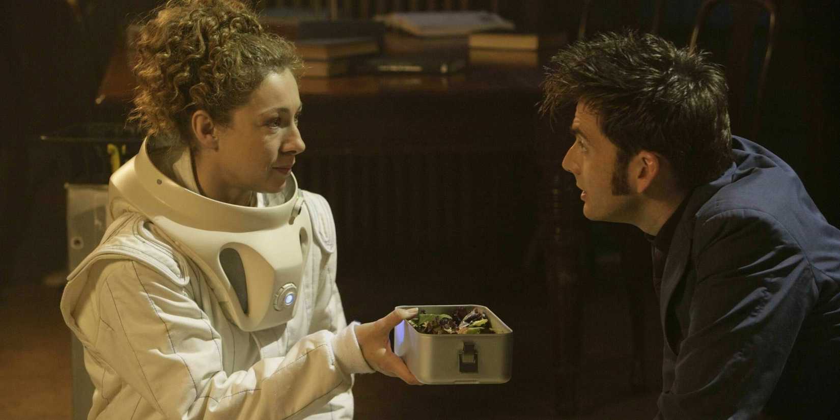 River Song offering the Tenth Doctor some food to trick the Vashta Nerada, as they kneel on the library floor, in the Doctor Who episode "Silence in the Library."