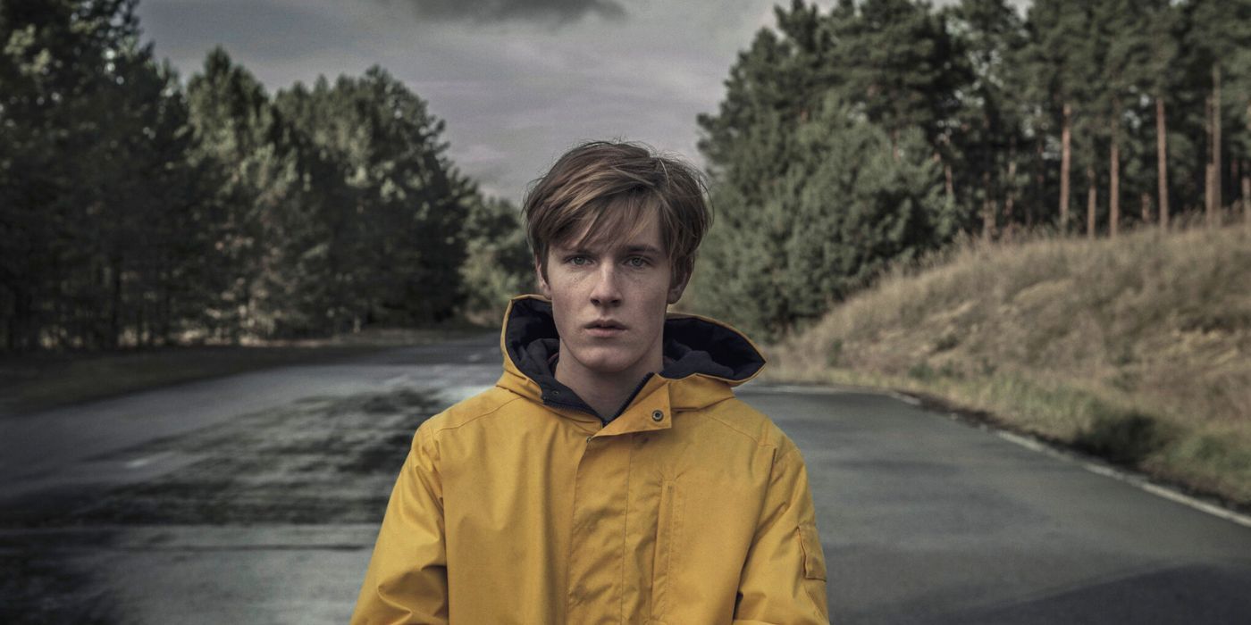 Jonas in the Dark television show, wearing a yellow coat and holding on a forest background
