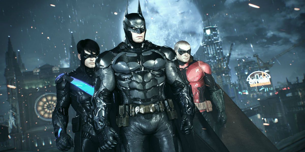 Batman, Nightwing, and Robin standing together on a roof in Arkham Knight's rainy Gotham City.