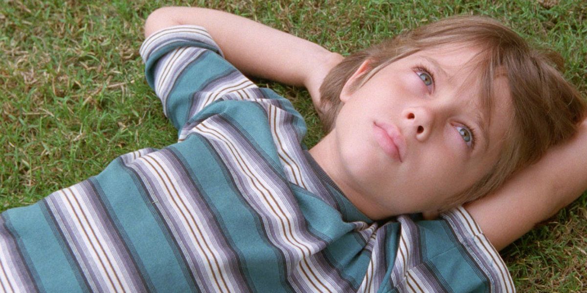 Criança Mason deitada na grama olhando para o céu em Boyhood