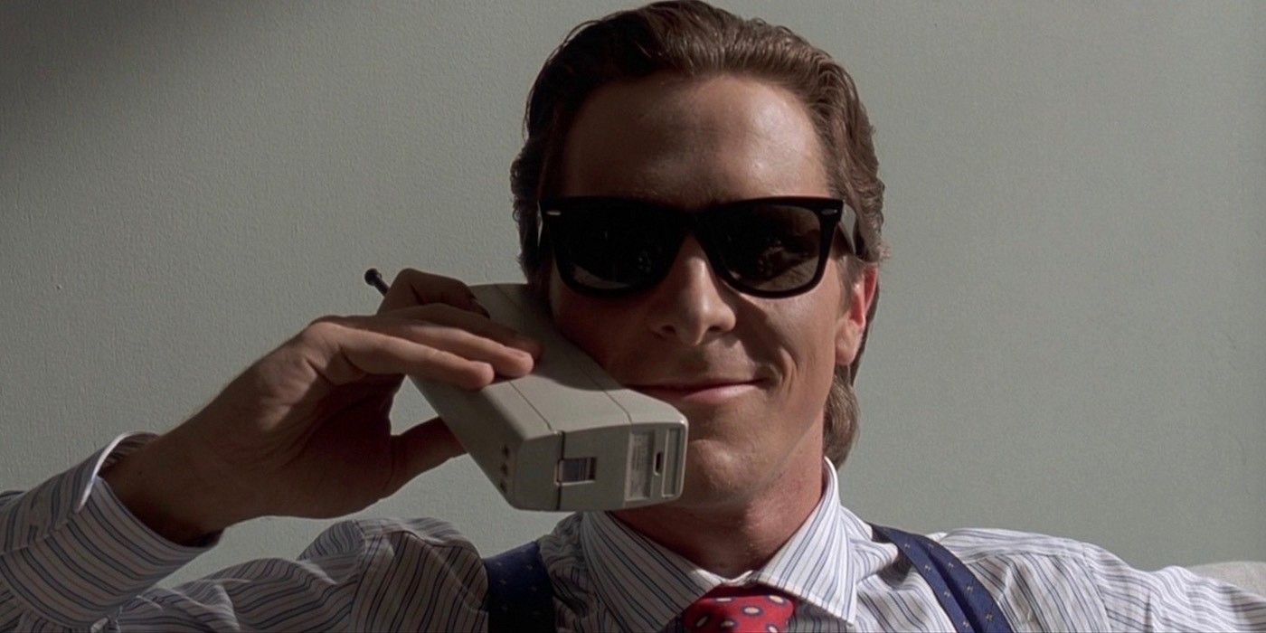 Patrick Bateman in American Psycho wearing a pair of sunglasses and talking on a huge 80s cell phone
