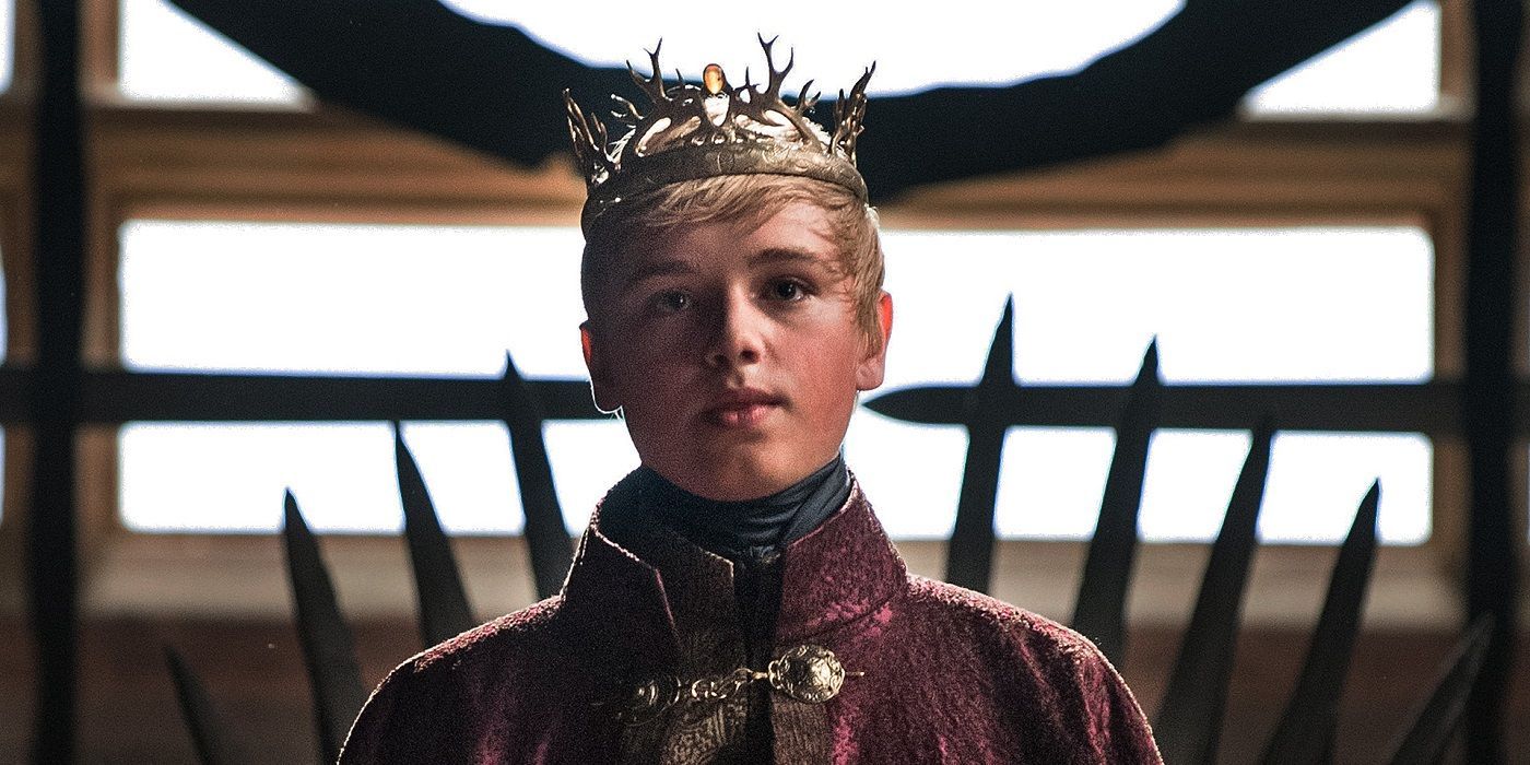 Tommen Baratheon wearing his crown and standing in front of the Iron Throne in Game of Thrones.
