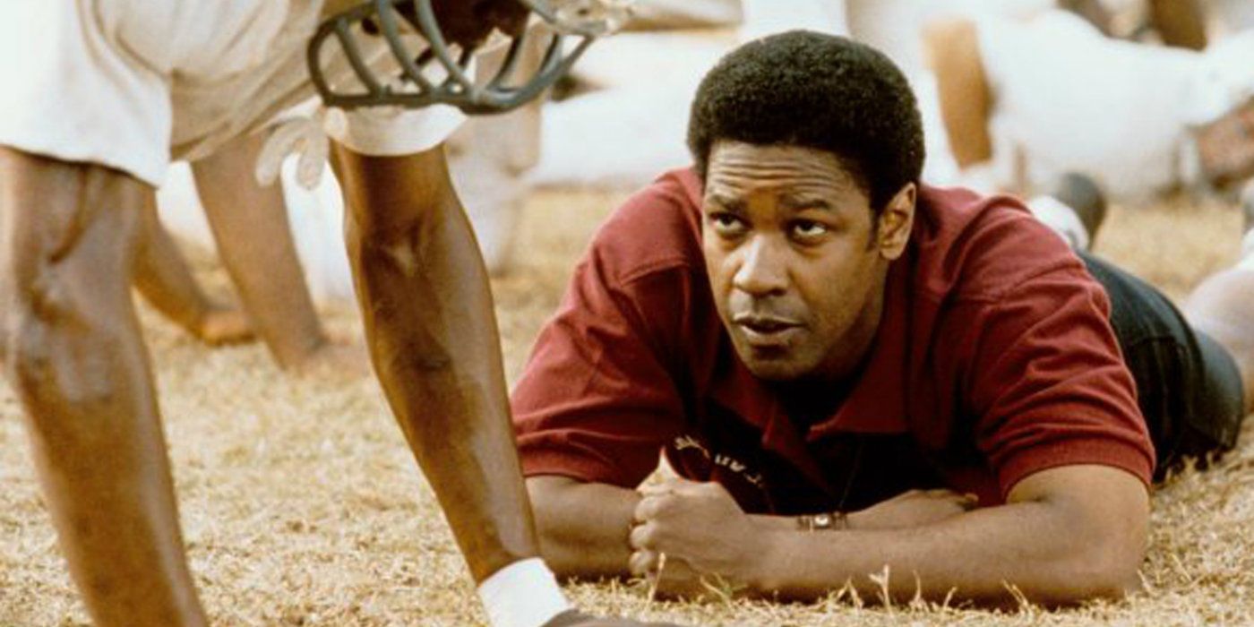 Denzel Washington lying on the ground and looking at a player in Remember The Titans