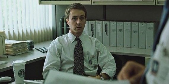 The Narrator is slumped at his desk with a Starbucks coffee in Fight Club