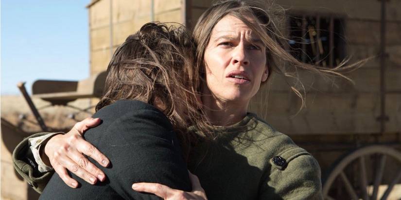 Hilary Swank in The Homesman looking into distance and holding daughter
