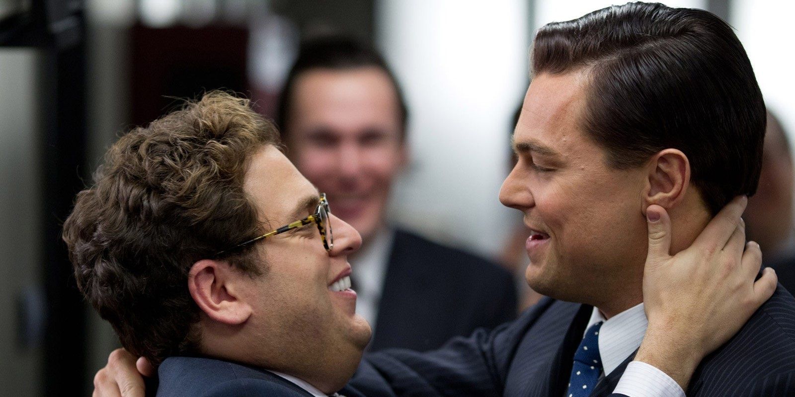 Leonardo DiCaprio as Jordan Belfort, and Jonah Hill hug in The Wolf of Wall Street